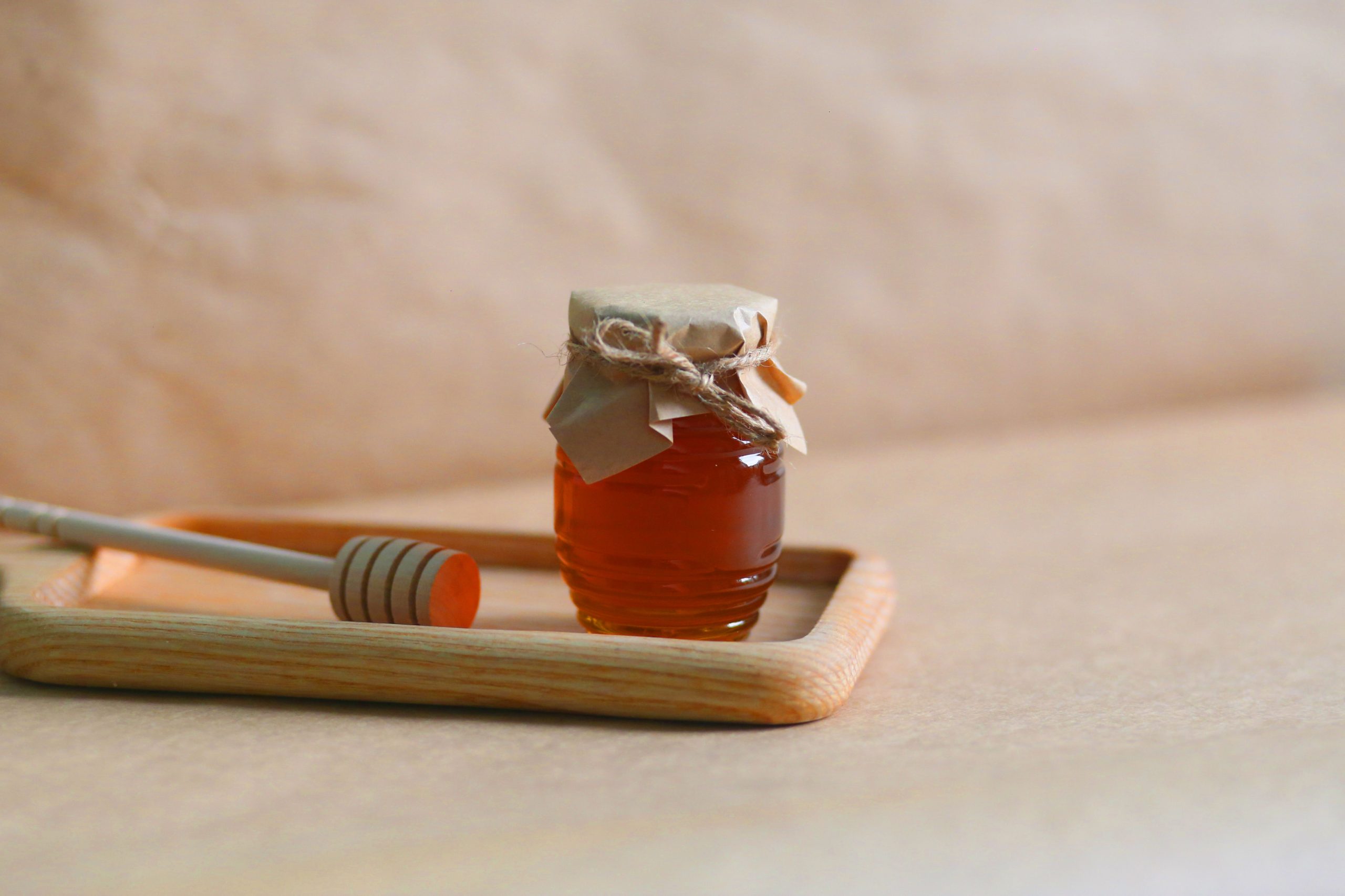 Скляна банка натурального меду з дерев’яною ложкою на кухонному столі